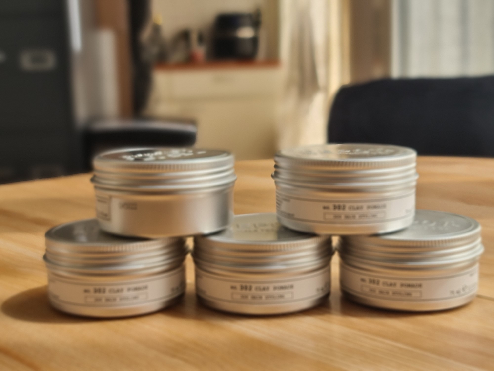 Tins of No. 302 Clay Pomade on a wooden table at Headz for Hair in The Hague