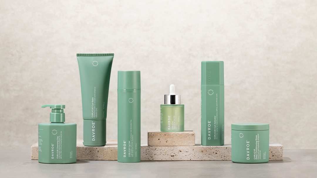 De Davroe CURLiCUE-serie: groene flessen, tubes en potjes op een stenen plateau