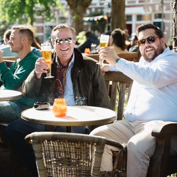 Gasten proosten lachend op het zonnige terras